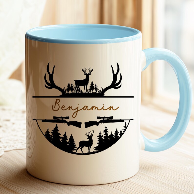 K&ouml;nnte beinhalten: Wei&szlig;er Keramikbecher mit hellblauem Innenraum und Griff. Der Becher zeigt ein schwarzes Silhouette-Design von Hirschen, Gewehren und B&auml;umen, mit dem Namen "Benjamin" in Schreibschrift.