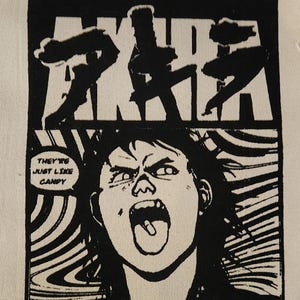May include: Black and white graphic print featuring the word "AKIRA" above a comic-style illustration of figures and a screaming person. The text "THEY'RE JUST LIKE CANDY" is in a speech bubble.