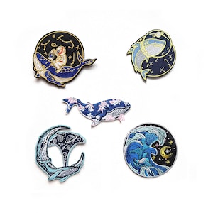 May include: Five embroidered iron-on patches featuring whales and ocean scenes. The patches are circular and feature a variety of colours, including blue, white, pink, and gold. The patches are perfect for adding a touch of whimsy to clothing, bags, or other fabric items.