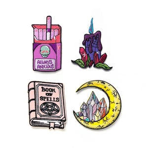 Pode incluir: Quatro patches bordados para passar a ferro com tema de bruxas. Os patches apresentam um maço de cigarros com o texto "Always Anxious", uma vela roxa com cristais, um livro rosa com o texto "Book of Spells", e uma lua crescente amarela com cristais.