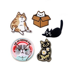 Può includere: Set di cinque toppe ricamate da stirare con diversi gatti. Le toppe sono di vari colori e stili, tra cui un gatto tigrato, un gatto nero con fiori, un gatto in una scatola e un gatto con il testo "Sono un gatto da interno".