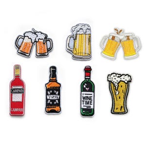 Può includere: Un set di sette toppe ricamate a tema bevande. I disegni includono due boccali di birra che brindano, un boccale con schiuma, due boccali, una bottiglia rossa di Campari, una bottiglia di whisky nera, una bottiglia di vino verde con etichetta Wine Time e un bicchiere da birra.