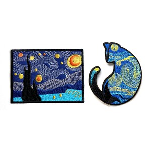 Può includere: Due toppe ricamate: una rettangolare, raffigurante "Notte stellata" di Van Gogh, e una toppa a forma di gatto con un design simile. Le toppe presentano fili blu, gialli e neri su sfondo bianco. La toppa a forma di gatto ha una coda ricurva.