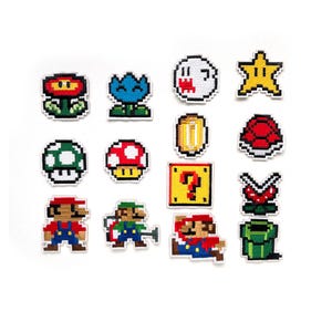 Può includere: Un set di 14 toppe ricamate da stirare con personaggi e oggetti del videogioco Super Mario Bros. Le toppe sono colorate e pixelate, e includono personaggi come Mario, Luigi e un Goomba, oltre a oggetti come un fungo, una stella e un blocco interrogativo.