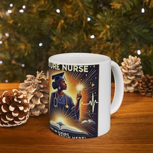 May include: White ceramic mug with a colorful illustration of a Black woman in a graduation cap and gown, holding a book and a glowing star. The text "FUTURE NURSE" is above the woman, and the text "DREAMS IN SCRUBS BEGIN HERE!" is below her.