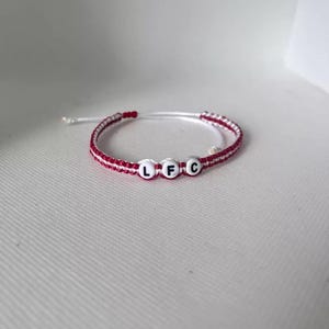 May include: Red and white braided bracelet with white beads spelling out "LFC".