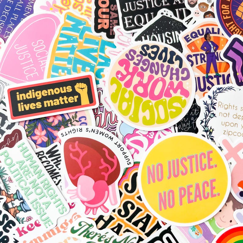 May include: A collection of colorful stickers with various social justice themes. The stickers feature phrases like "Indigenous Lives Matter," "No Justice, No Peace," and "Social Work Changes Lives." The stickers are in various shapes and sizes.