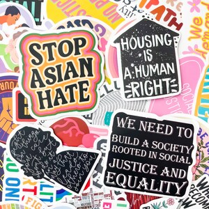 May include: A collection of colorful stickers with various social justice messages. One sticker reads "STOP ASIAN HATE" in bold black letters with a pink, orange, and green border. Other stickers include "HOUSING IS A HUMAN RIGHT" and "WE NEED TO BUILD A SOCIETY ROOTED IN SOCIAL JUSTICE AND EQUALITY."
