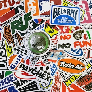 Könnte beinhalten: Eine Sammlung bunter Aufkleber mit verschiedenen Logos und Texten. Die Aufkleber umfassen Marken wie Bel-Ray, Gulf und Twin Air. Einige Aufkleber zeigen Rennsportmotive, andere Texte wie "No Fun" und "Offset is Everything."