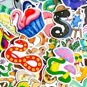 Könnte beinhalten: Eine Sammlung farbenfroher Aufkleber mit Cartoon-Schlangen und anderen skurrilen Designs. Die Aufkleber zeigen eine Schlange, die auf einer Leinwand malt, eine Schlange mit Hut und einen schlangenförmigen Cupcake mit Apfel. Weitere Aufkleber zeigen Pilze und Blumenmuster.