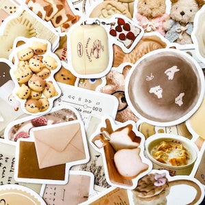 May include: A collection of various stickers with a food theme. The stickers include images of teddy bears, cat-shaped cookies, bread, a plate with small white figures, and a bottle with the text "Capture beauty".