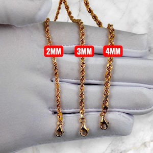 K&ouml;nnte beinhalten: Drei goldfarbene Seilketten in verschiedenen St&auml;rken werden gezeigt. Die Ketten sind 2 mm, 3 mm und 4 mm dick, jede mit einem Karabinerverschluss. Die Ketten werden vor einem wei&szlig;en Hintergrund gezeigt.
