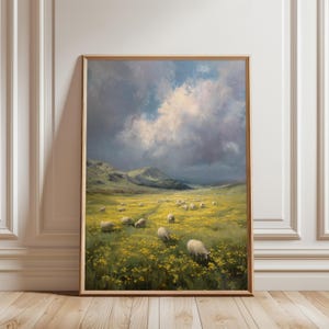 Puede incluir: Una pintura de paisaje enmarcada representa un campo de flores amarillas con ovejas pastando bajo un cielo dramático. La obra presenta colinas verdes onduladas en el fondo y un cielo nublado con toques de azul y gris. El marco es de color marrón claro.
