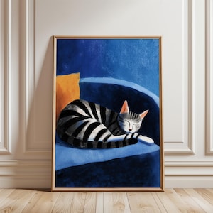 May include: A framed art print of a sleeping cat. The cat has black and gray stripes and is curled up on a blue chair with an orange pillow. The artwork is in a minimalist style with a wooden frame.