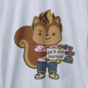 Puede incluir: Camiseta blanca con una ardilla de dibujos animados con una camisa teñida con tinte y vaqueros azules, sosteniendo un cartel que dice "ya'll not normal". La ardilla es marrón con una cara sonriente. El cartel tiene corazones morados.