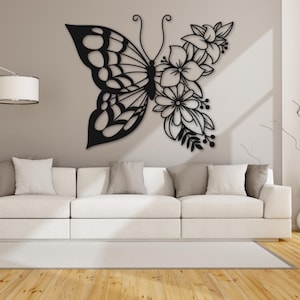 May include: Black metal wall decor featuring a butterfly with intricate details and floral accents. The butterfly is positioned with its wings spread, and the flowers are clustered around its body.