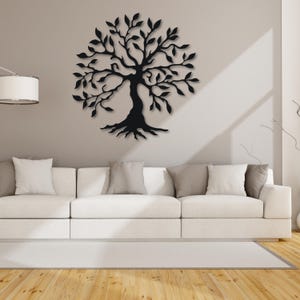 May include: Black metal wall art depicting a stylized tree with branches and roots. The tree is mounted on a white wall above a white couch.