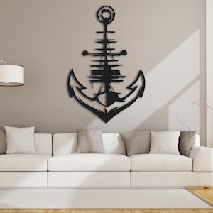 Peut inclure: Décoration murale en métal noir en forme d'ancre avec un mât de navire et des voiles à l'intérieur de l'ancre. L'ancre est montée sur un mur gris clair au-dessus d'un canapé blanc.