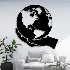 May include: Black metal wall art depicting a hand holding a globe of the Earth. The globe is detailed with continents and oceans.