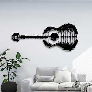 Könnte beinhalten: Schwarze Silhouette einer Akustikgitarre mit einem Sonnenuntergang und Bäumen im Inneren des Gitarrenkörpers. Die Gitarre spiegelt sich in einem Gewässer.