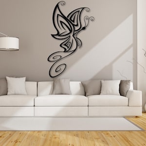 May include: Black metal wall decor featuring a stylized butterfly design with intricate details. The butterfly is shown in flight with its wings spread wide. The decor is mounted on a white wall above a white couch.