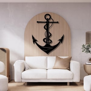 Könnte beinhalten: Eine schwarze Anker-Wanddekoration aus Metall mit einem Seildesign, montiert auf einer runden Holzplatte. Der Anker hängt über einem weißen Sofa in einem Wohnzimmer.