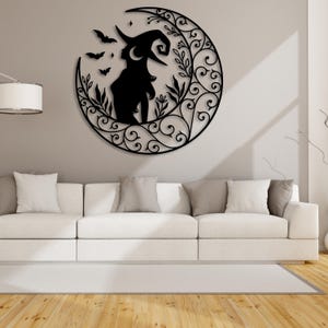 May include: Black metal wall decor featuring a silhouette of a witch with a pointed hat standing in a crescent moon with floral details.