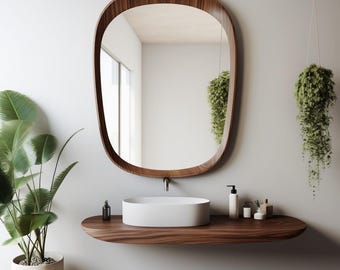 May include: A modern bathroom scene featuring a large, oval-shaped wooden-framed mirror. Below, a floating wooden shelf holds a white oval sink and toiletries. Green plants add a natural touch to the minimalist design.
