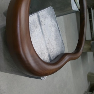 May include: A close-up of a brown wooden chair armrest with a smooth, polished finish.
