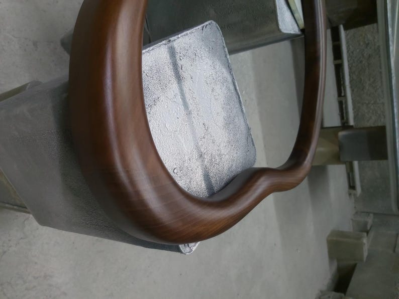May include: A close-up of a brown wooden chair armrest with a smooth, polished finish.
