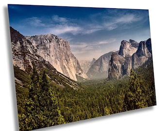 Könnte beinhalten: Ein Panoramablick auf ein Tal im Yosemite-Nationalpark, Kalifornien. Das Tal ist umgeben von hoch aufragenden Granitfelsen, mit einem dichten Wald im Vordergrund. Der Himmel ist strahlend blau mit fluffigen weißen Wolken.