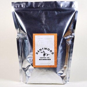 Könnte beinhalten: Ein silberner Folienbeutel mit einem Etikett, auf dem "Dentwood Coffee Co. 37.500° N, 77.337° W" und eine kleine Kieferngrafik steht. Das Etikett ist orange mit schwarzem Text.