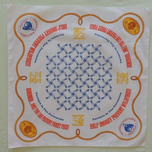 May include: White bandana with a rope border and a blue and white checkered pattern in the center. The bandana has the text "Help Smokey Prevent Wildfires!" and "Remember... Only You Can Prevent Forest Fires!" printed on it. The bandana also features the Smokey Bear logo and the Professional Rodeo Cowboys Association logo.