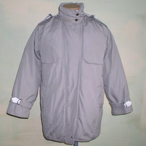 May include: A gray, zippered jacket with a high collar and a white trim around the collar, cuffs, and pockets.