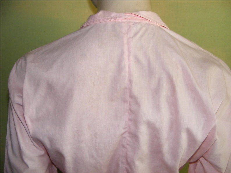 May include: A pale pink long-sleeved shirt with a button-up collar.