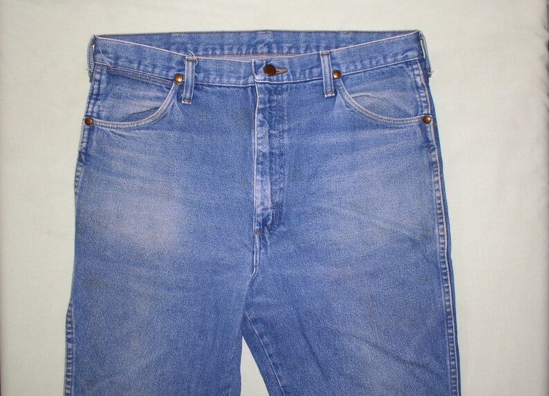 May include: A pair of blue denim jeans with a button fly and belt loops. The jeans have a faded look and are made of a soft, comfortable material.
