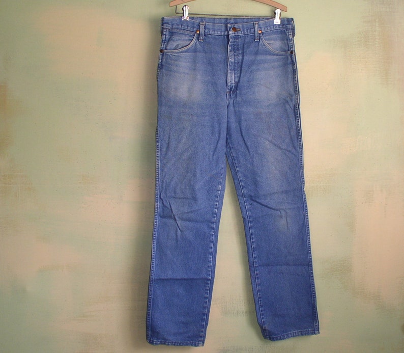 May include: A pair of blue denim jeans with a straight leg fit. The jeans have a button fly and belt loops.
