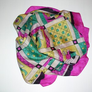 May include: A pink silk scarf with a geometric pattern in black, white, green, and yellow. The pattern features squares, circles, and abstract shapes.