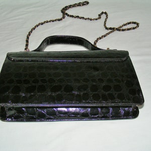 May include: A black crocodile embossed leather handbag with a gold chain strap.