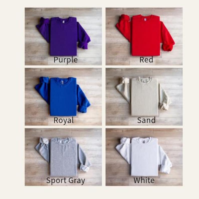 May include: A collection of six crewneck sweatshirts in various colors: purple, red, royal blue, sand, sport gray, and white. Each sweatshirt is neatly folded, with the color name displayed below.