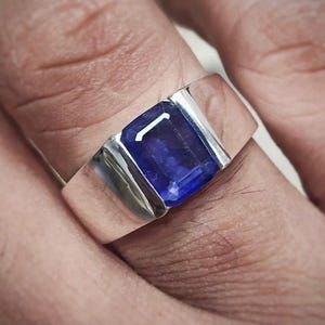 May include: A silver ring with a large, rectangular, dark blue gemstone.