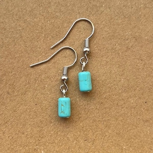 May include: A pair of silver earrings with turquoise blue rectangular stones.