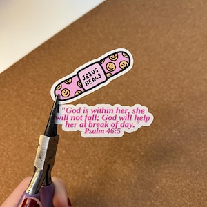 May include: A pink sticker in the shape of a capsule with the words "JESUS HEALS" and smiley faces. A second sticker with the text "God is within her, she will not fall; God will help her at break of day. Psalm 46:5".