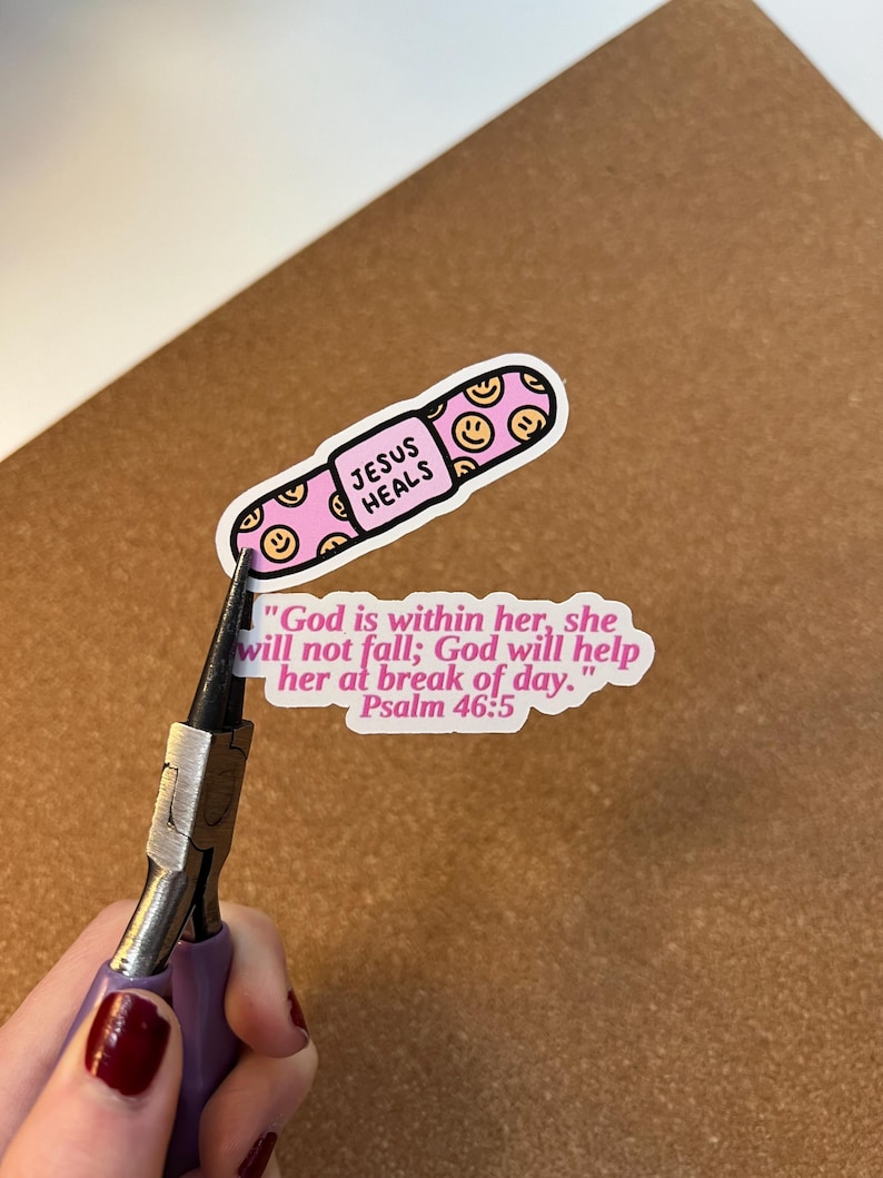 May include: A pink sticker in the shape of a capsule with the words "JESUS HEALS" and smiley faces. A second sticker with the text "God is within her, she will not fall; God will help her at break of day. Psalm 46:5".