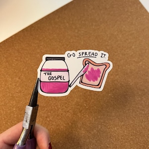 May include: A white ceramic mug with a black handle and the text "But First, Coffee" in a bold, black font. The mug is set against a blurred background, suggesting a cosy setting.