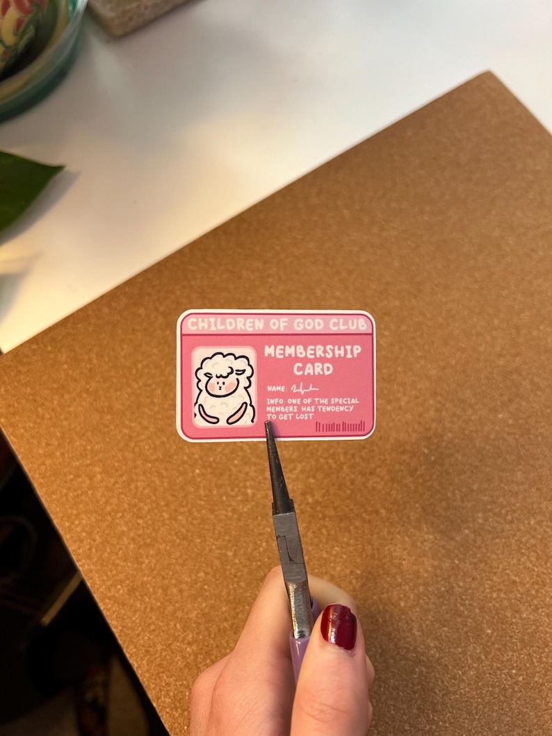 May include: A pink membership card for the "Children of God Club" featuring a sheep graphic. The card's text reads: "INFO: ONE OF THE SPECIAL MEMBERS HAS TENDENCY TO GET LOST."