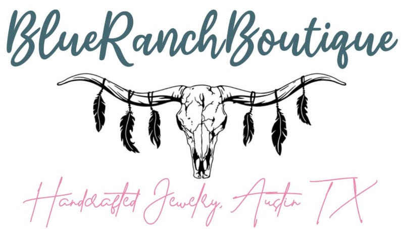 May include: The Blue Ranch Boutique logo displays a steer skull with hanging feathers. The text above reads "Blue Ranch Boutique" in teal script, and below, "Handcrafted Jewelry, Austin TX" in pink script.