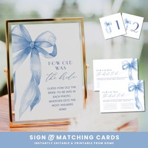 May include: A gold-framed sign and matching cards with a blue watercolor bow design. The sign reads "How Old Was the Bride?" with instructions for a bridal shower game. Two cards are numbered 1 and 2, and two other cards have fill-in-the-blank prompts.