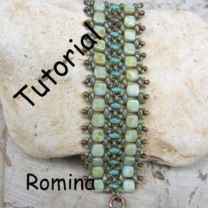 May include: A green, blue, and copper beaded bracelet with a copper clasp. The bracelet is on a light brown rock with the word "Tutorial" written in black and the word "Romina" written in black below the bracelet. The text "www.LiriGal.com" is written in black below the word "Romina".
