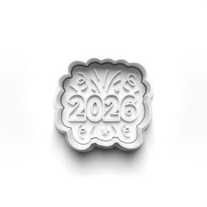 May include: A white plastic cookie cutter shaped like a cloud, featuring the year 2026. The design includes fireworks, stars, and swirls, ideal for creating celebratory biscuits for the new year.